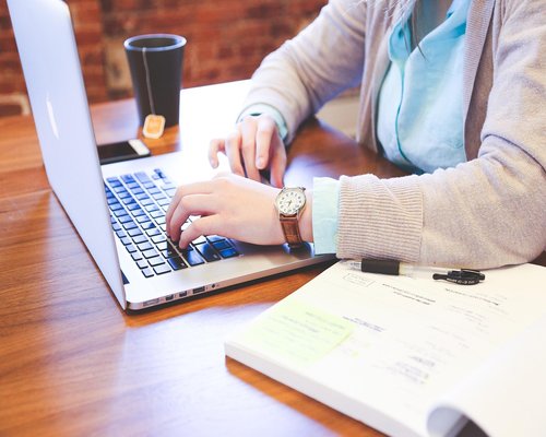 A professional typing on a laptop with an organized workspace environment and proper ergonomic posture